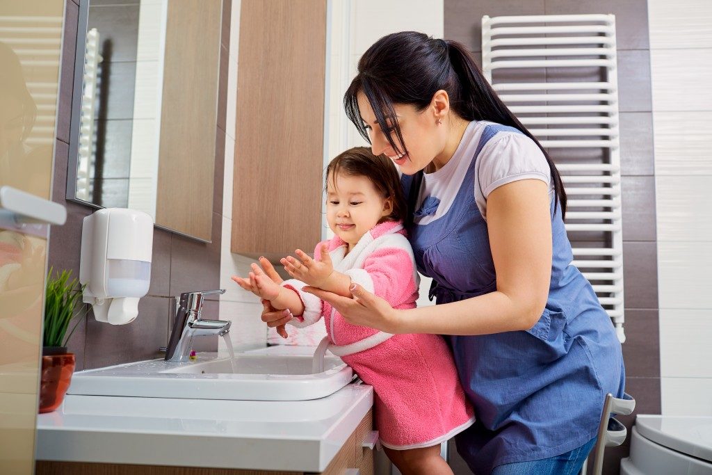 mother helping her child wash her hands